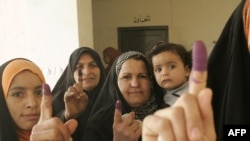 Iraqi women show their ink-stained fingers after casting their votes at a polling station in Baqubah.