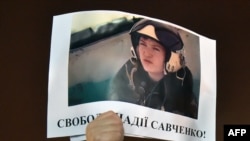 A demonstrator in Kyiv holds aloft a picture of the Ukrainian army officer captured by pro-Russian insurgents and taken to Russia, Nadia Savchenko, with the words "Free Nadia Savchenko."
