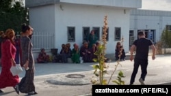 Adamlar boş bankomatlaryň öňünde oturyp, pula garaşýarlar. Bäherden, Türkmenistanyň Ahal welaýaty, awgust, 2020. 