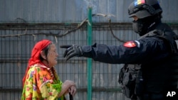 O femeie romă este admonestată de un polițist la un raid împotriva colectării ilegale de metale, la Vidra, în România, în aprilie 2021.