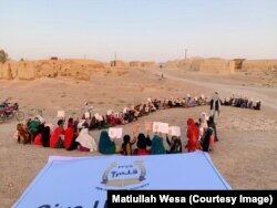 Un grup de copii primește cărți și articole de papetărie în timpul unei întâlniri școlare, în provincia Kandahar. Fotografie realizată la data de 1 august 2021.