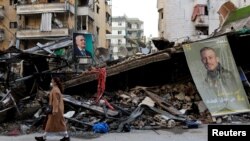 زنی در حال عبور از کنار ویرانه‌های برجا مانده از حملات هوایی اسرائیل به بیروت، پایتخت لبنان