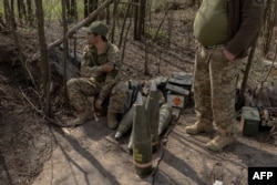 Soldați ucraineni din unitatea de artilerie a regimentului Skala așteaptă lângă obuze, în timp ce colegii lor trag cu un obuzier M109 spre pozițiile rusești din estul regiunii Donețk, la 23 aprilie 2025