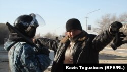 Сотрудник полиции обыскивает задержанного  мужчину. Город Жанаозен Мангистауской области, 19 декабря 2011 года. 