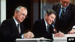 Liderul sovietic Mihail Gorbaciov (stânga) și președintele SUA Ronald Reagan semnând tratatul pentru eliminarea rachetelor de rază medie și scurtă cu încărcătură nucleară în cadrul summit-ului de la Washington, 8 decembrie 1987