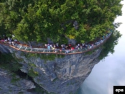 Туристтер жапайы жаратылышка айнек көпүрөдө туруп суктанышууда. Кытай, 2-август 2016