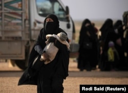 Жена со бебе во рацете во близина на селото Багуз, последното упориште на Исламската држава, февруари 2019 година.