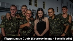 Anastasia Prykhodko poses with Ukrainian soldiers on the front line.