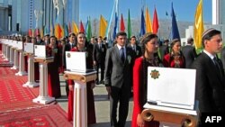 Aşgabatda geçirilen bir köpçülik çäresinde adamlaryň gapdalynda hatara düzülip goýlan laptop kompýuterler. Arhiw suraty. Illýustrasiýa.