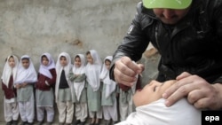 په اسلام اباد کې یو روغتیايي کارکوونکی په ښوونځي کې یوې ماشومې ته د ګوزڼ واکسیني څاڅکي ورکوي - انځور له ارشیفه. 