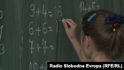 O elevă scrie pe tablă rezultatele unor adunări (imagine din arhiva RFE/RL).