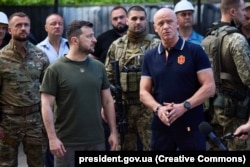 უკრაინის პრეზიდენტი ვოლოდიმირ ზელენსკი (მარცხნივ) და ოდესის მერი გენადი ტრუხანოვი რუსეთის რაკეტის მიერ დაზიანებული მრავალსართულიანი საცხოვრებელი შენობის წინ. ოდესა, 2022 წლის 18 ივნისი