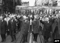 ЧСКПнын лидери Александр Дубчек (оңдон үчүнчү) жана Чехословакиянын президенти, генерал Лүдвиг Свобода (солдон үчүнчү) майрамдык парадга катышкан калайык арасында. Прага шаары. 01.5.1968. (Маскөөчүл Густав Гусак, солдон экинчи, 1969-жылы Дубчектин ордуна ЧСКПны жетектеп калган).