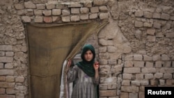A Pashtun girl looks out from the doorway of her family dwelling in Peshawar.