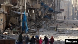 Siriýada ýumrulan jaýlaryň arasyndaky adamlar