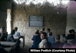 Afghan students learn chemistry in a mud-walled classroom.