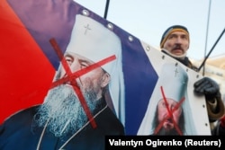 Un activist naționalist ucrainean cu un banner în care cere ca clericii proruși ca Onufrei (st.) să fie schimbați pe ucraineni aflați în închisori rusești (2018)