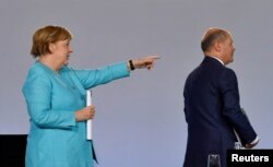Cancelarul Angela Merkel gesticulează în spatele ministrului de finante și vice- cancelarului, Olaf Scholz, la o conferință despre măsurile împotriva coronavirusului, Berlin, 2 iunie, 2020.