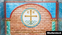 Пам'ятний знак у Києві. Місце хрещення України-Русі. Панно з кераміки, що зображує хрест на водах Дніпра (символ хрещення) і напис: «Тут в 988 році на злитті Дніпра і Почайни хрестилася Русь»