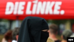 Ниқаб киген әйел Германия "Солшыл партиясының" үгіт-насихатын тыңдап тұр. 2016 жылғы қыркүйек.