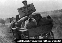 Представитель советской власти везет конфискованное у крестьян зерно на пункт сдачи зерна. Репродукция. УССР, 1933 год