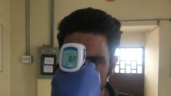 کارکن صحی در هرات در حال دیدن درجه تب افغانی که از ایران برگشته است.