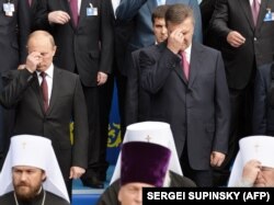 Президент Росії Володимир Путін (ліворуч) і президент України Віктор Янукович (праворуч) хрестяться під час богослужіння, присвяченого 1025-річчю Хрещення України-Русі. Київ, 27 липня 2013 року