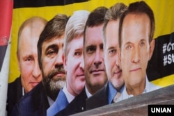 Плакат с изображением украинских олигархов и президента России Владимира Путина во время акции «Стоп Реванш» возле Верховной Рады Украины. Первый в шеренге – Виктор Медведчук. За ним Дмитрий Фирташ, Сергей Левочкин, Ринат Ахметов и Вадим Новинский. Киев, 16 января 2018 года