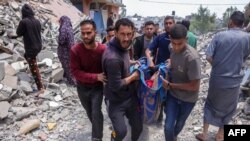 Mai mulți palestinieni cară o persoană rănită în urma unui atac israelian, 27 mai 2025.