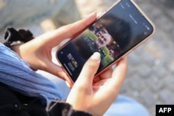 Иранская женщина в смартфоне смотрит на фотографию лидера Корпуса стражей исламской революции Ирана майора Хоссейна Салами, погибшего в результате израильского удара 13 июня 2025 гола по Тегерану