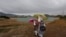 Afghan school girls hold umbrellas to shelter from rain on outskirt of Kabul on May 15.