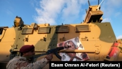 Un membru al Armatei Naționale Libiene comandată de Khalifa Haftar ia la țintă portretul președintelui turc Tayyip Erdogan