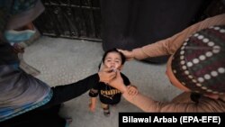 په پېښور کې یوه روغتیايي کارکوونکې ماشوم ته واکسیني څاڅکي ورکوي - پخوانی انځور. 