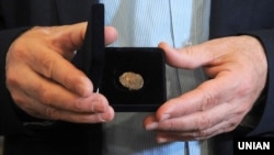 Директор Центру археології Києва Інституту археології України Михайло Сагайдак демонструє реліквію періоду України-Русі – печатку князя Святослава Хороброго (правління: 964–972) із зображення двозуба (праобразу державного герба України – тризуба). Київ, 11 травня 2016 року 