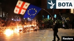 Një protestues valëvit flamurin e Gjeorgjisë dhe atë të BE-së gjatë protestave pas mbajtjes së zgjedhjeve lokale. Tbilisi, 4 tetor 2025. 