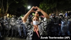 Жена стои пред полицијата за време на протестот против таканаречениот „руски закон“ во близина на зградата на парламентот во Тбилиси, Грузија, на 1 мај 2024 година.