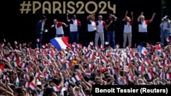 Люди збираються у фанзоні Олімпійських ігор у Парижі перед Ейфелевою вежею, у садах Трокадеро в Парижі, щоб подивитися церемонію закриття ігор у Токіо.  Франція, 8 серпня 2021 року.