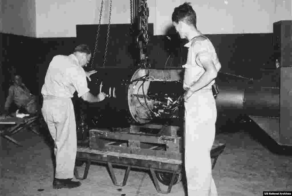 Bomba atomică numită „Little Boy”, inspectată după asamblarea pe insula Tinian în august 1945.Piesele pentru prima armă nucleară utilizată în luptă au fost transportate separat, în condiții de strictă confidențialitate, și aduse pe insula Tinian în iulie 1945, unde bomba a fost asamblată.