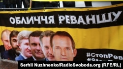 Плакат із зображенням українських олігархів і президента Росії Володимира Путіна під час акції «Стоп Реванш» біля Верховної Ради України. Перший у шерензі – Віктор Медведчук. Київ, 16 січня 2018 року 