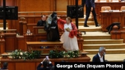 Senatoarea Diana Șoșoacă în Parlament, amenințându-l pe fostul premier PNL Florin Cîțu ( la tribună) că merită să fie băgat într-un sac negru și aruncat într-o groapă comună.