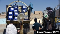 Employees of the Afghan Independent Election Commission (IEC) unload ballot boxes from a turck at a polling centre ahead of legislative election in Kandahar Province on October 26.