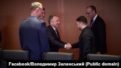  Украина президенті Владимир Зеленский (оң жақта) АҚШ президентінің арнайы өкілі Стивен Уиткоффпен қол алысып тұр. Берлин, 14 желтоқсан, 2025 жыл.