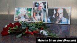 Photographs of journalists Orkhan Dzhemal (right), Kirill Radchenko (center) and Aleksandr Rastorguyev are seen at a small memorial to the slain jounalists outside the Central House of Journalists in Moscow.