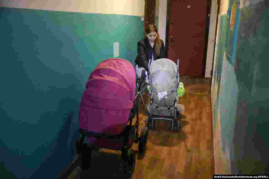 Дівчина з дитячими візками в коридорі житлового будинку укривається від безпілотників