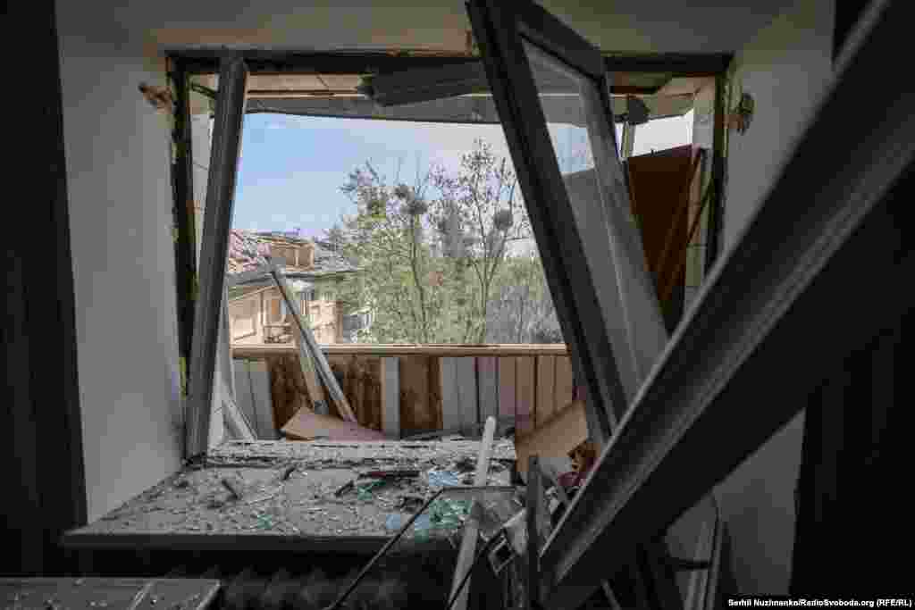 Вибуховою хвилею вибило віконну шибку, вирвало раму та пошкодило балкон однієї з квартир. На задньому плані видно пошкоджений дах сусіднього будинку