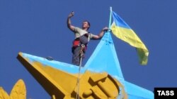 A Moscow city worker takes a selfie while atop the Kotelnicheskaya Embankment building in Moscow to remove the Ukrainian flag mounted there overnight on August 19-20.