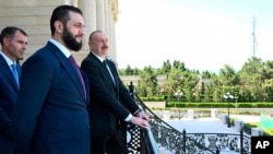 Azerbaijani President Ilham Aliyev (right) and Syria's interim president, Ahmad al-Sharaa, stand on a balcony during their meeting in Baku on July 12