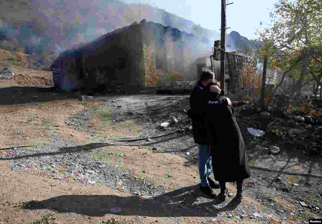 An ethnic Armenian couple embraces while watching their home burn in Charektar/Caraktar.