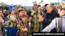 Нурсултан Назарбаев в бытность президентом Казахстана в окружении одетых в национальные костюмы людей на мероприятии в столице в День единства народа Казахстана. 1 мая 2018 года.
