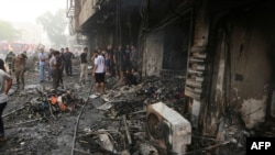 Iraqis inspect the damage at the site of a suicide car bombing claimed by the Islamic State group on July 3, 2016 in Baghdad's central Karrada district. The blast, which ripped through a street in the Karrada area where many people go to shop ahead of the